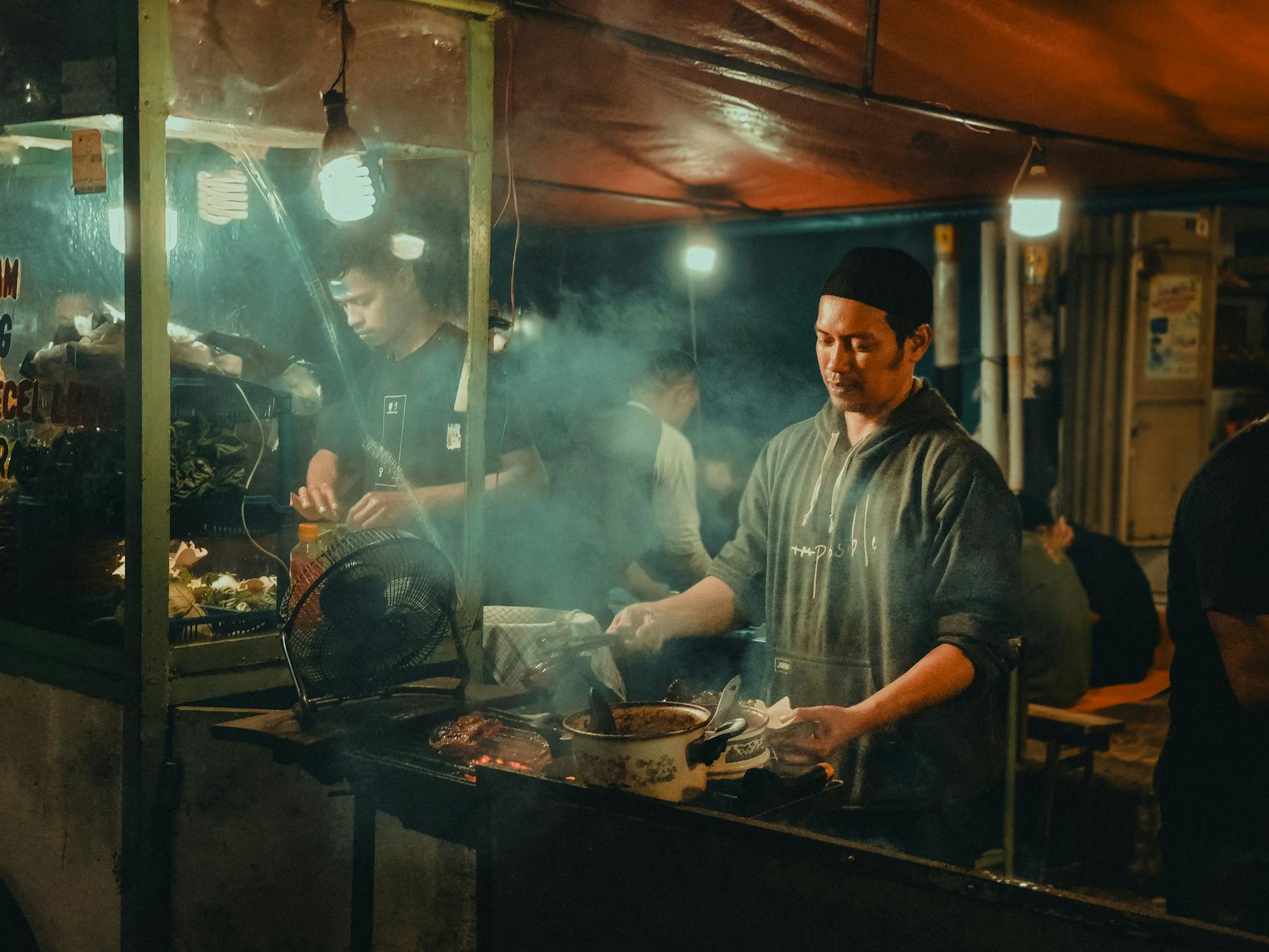 Indonesian street food vendor preparing dishes at night market