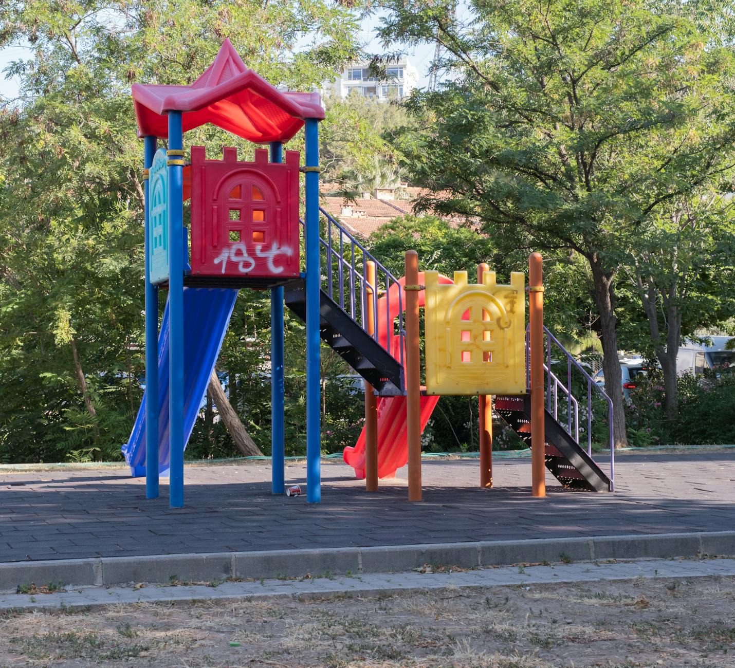 Young children climbing and sliding on a brightly coloured outdoor playground frame