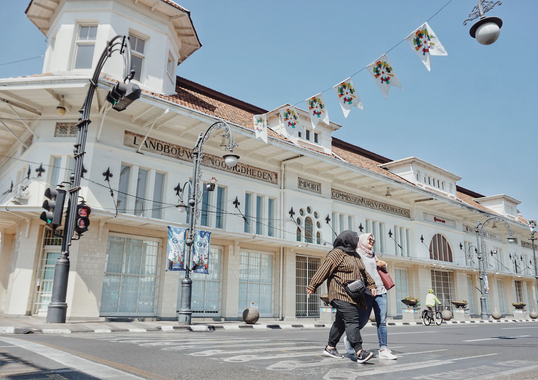 Pedestrians crossing in front of a white colonial-era building in central Bandung on a Bandung weekend getaway from Jakarta