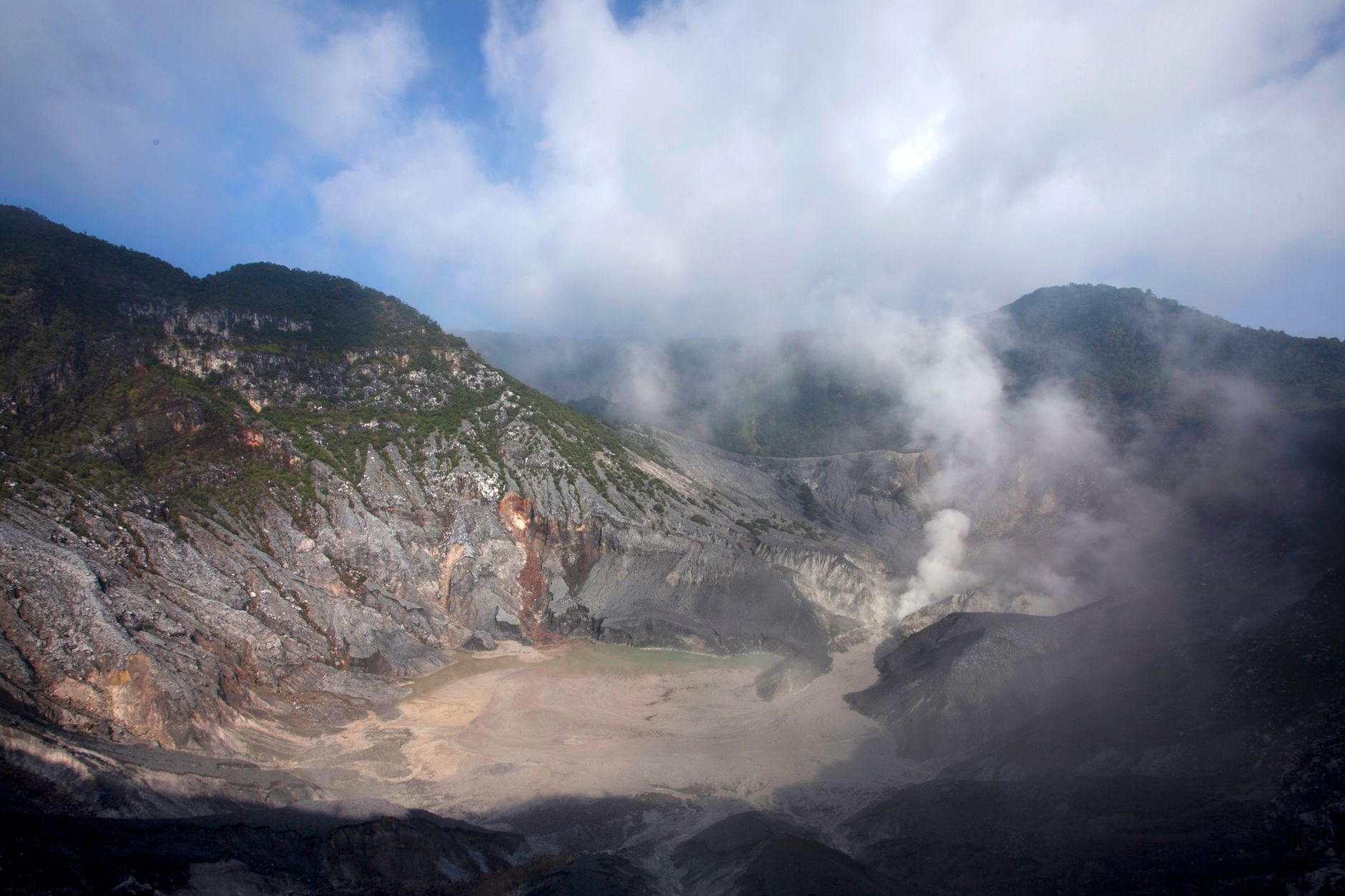 Steam rising from the grey crater floor of Tangkuban Perahu volcano north of Bandung