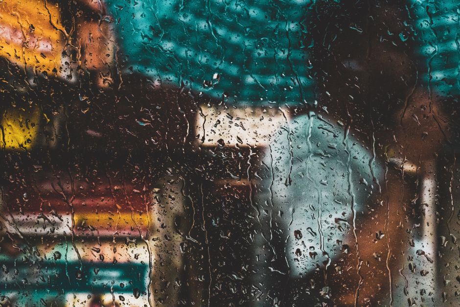 Heavy monsoon rain streaking down a window overlooking a Jakarta street during wet season