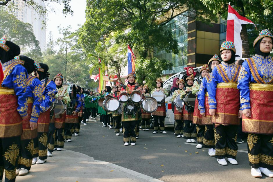A marching band in traditional dress parades through central Jakarta during a public holiday celebration