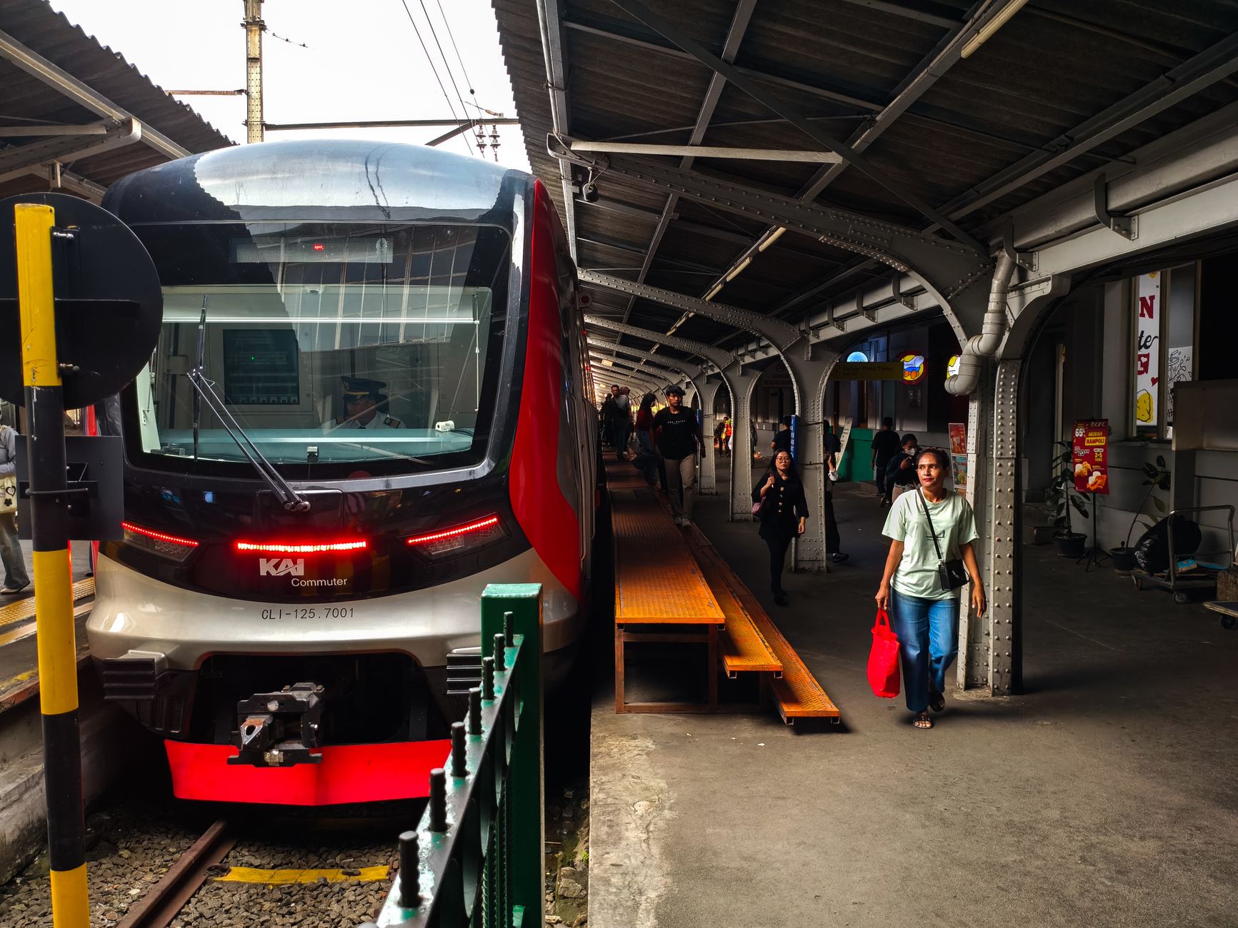 A red-and-white KAI Commuter Line train waiting at a Jakarta station platform