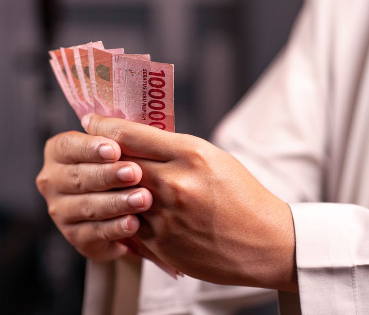 Hand holding a fan of Indonesian rupiah 100,000 banknotes after a currency exchange in Jakarta