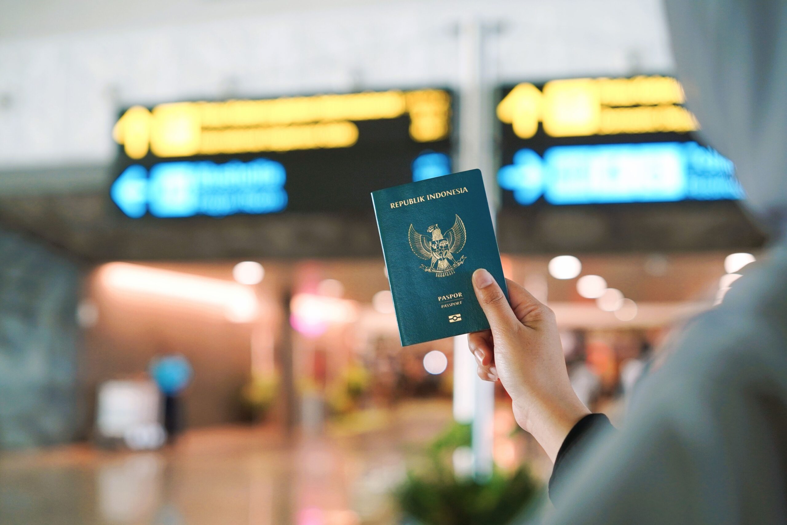 Traveller holding an Indonesian passport in an airport arrivals hall, illustrating passport validity rules under Indonesia visa requirements