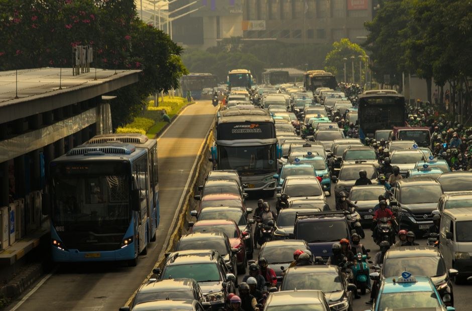 Heavy traffic congestion with a TransJakarta bus and motorbikes queued on a Jakarta road