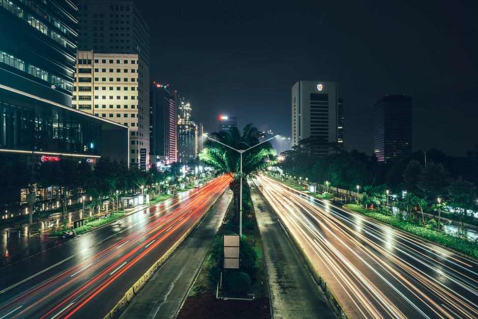 Long exposure of Jakarta skyscrapers and light trails from traffic on a wide road at night