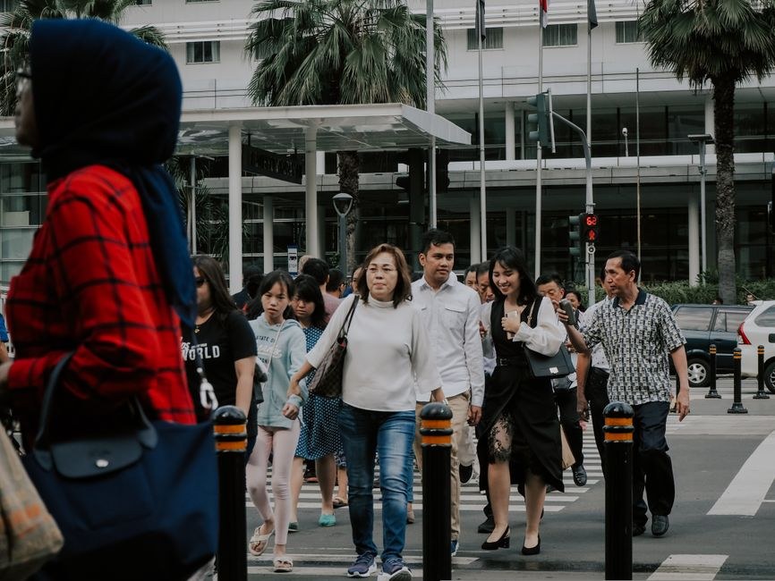 Group of pedestrians using a marked crossing on a busy central Jakarta street