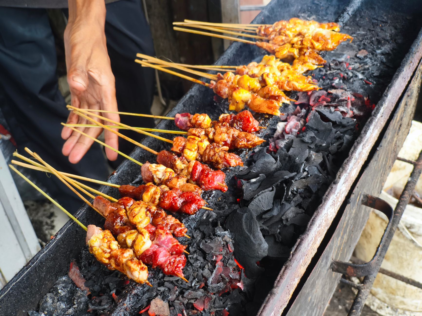 Satay skewers grilling over charcoal at a Jakarta late night food stall