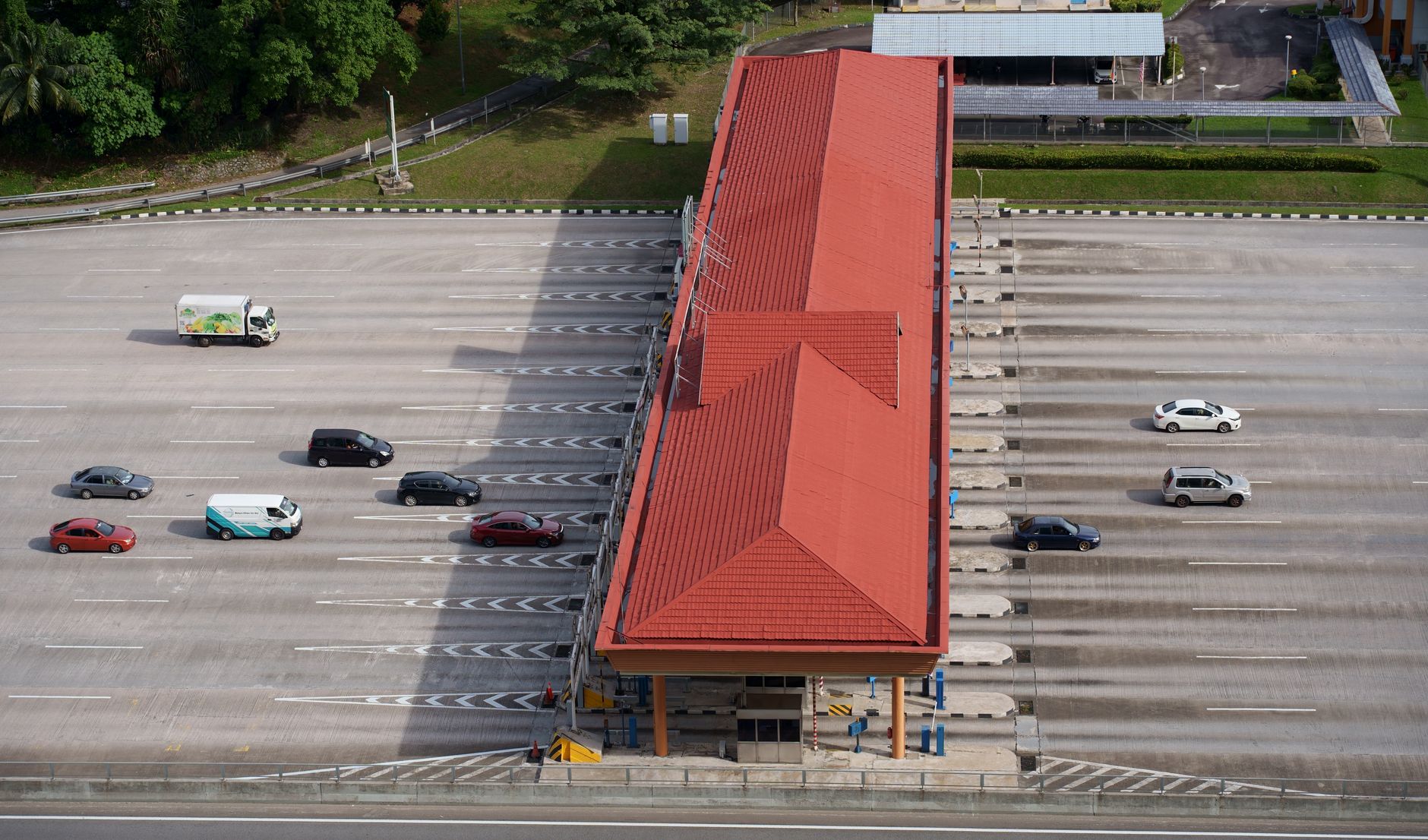 Aerial view of cars and trucks passing through a multi-lane Indonesian toll plaza