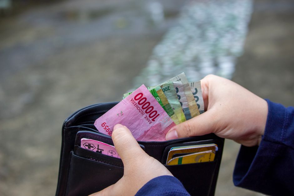 Hand holding Indonesian rupiah banknotes pulled from a wallet