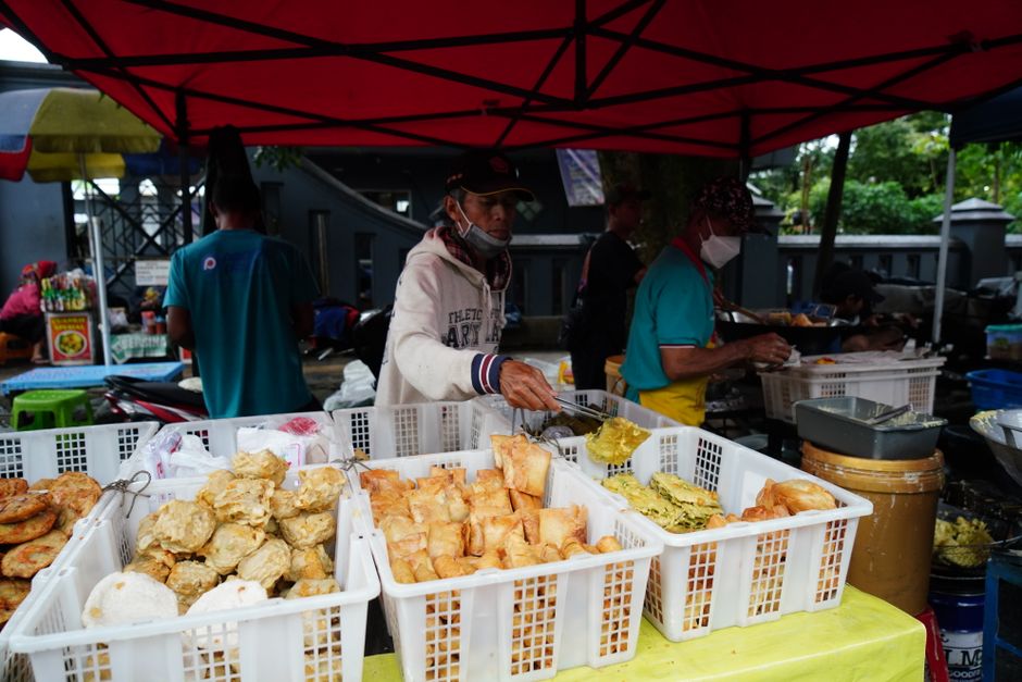 Street food vendor serving fried snacks from baskets at an Indonesian food stall