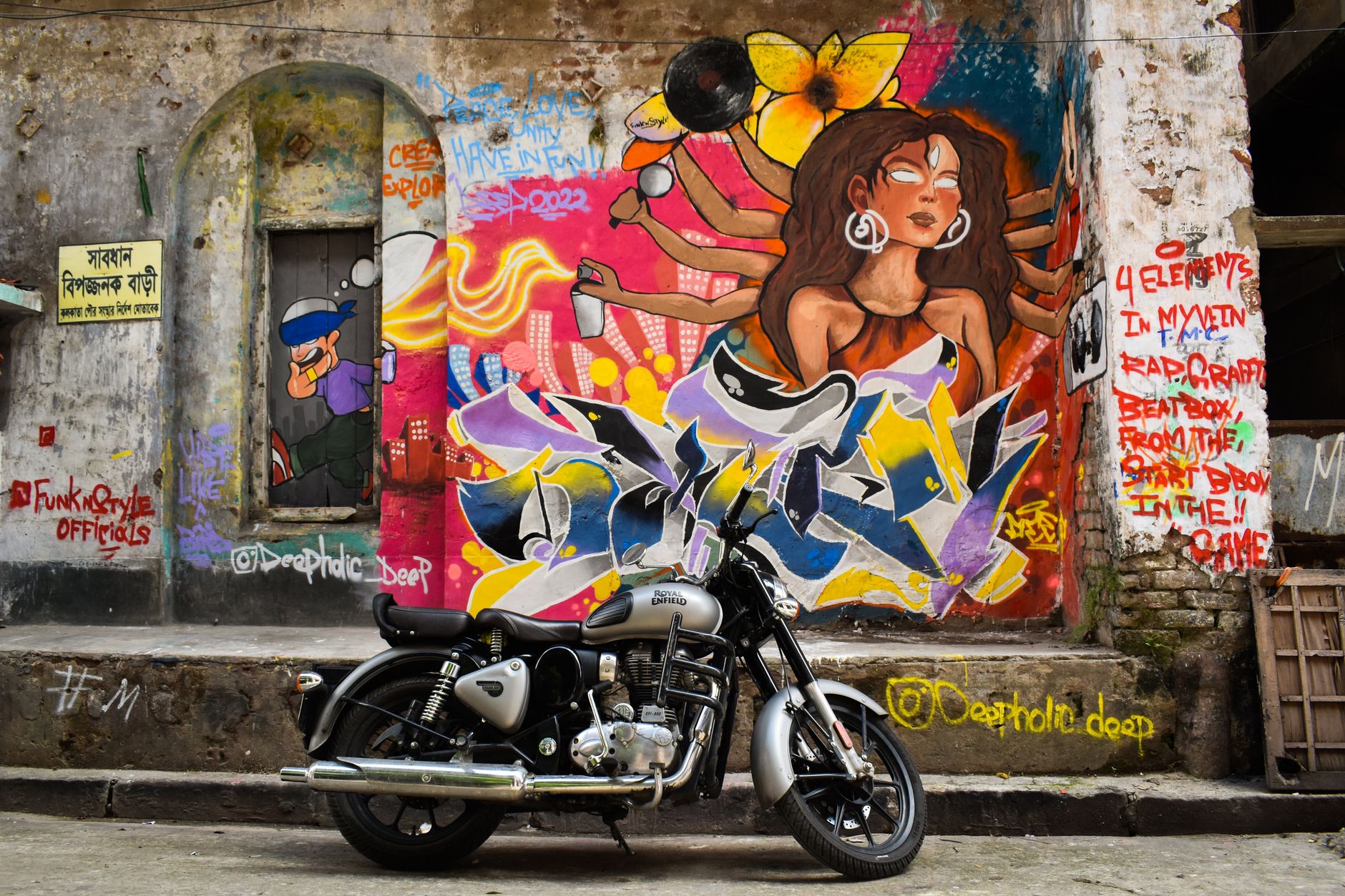 A colourful street mural painted on a wall with a motorbike parked in front of it in Kemang