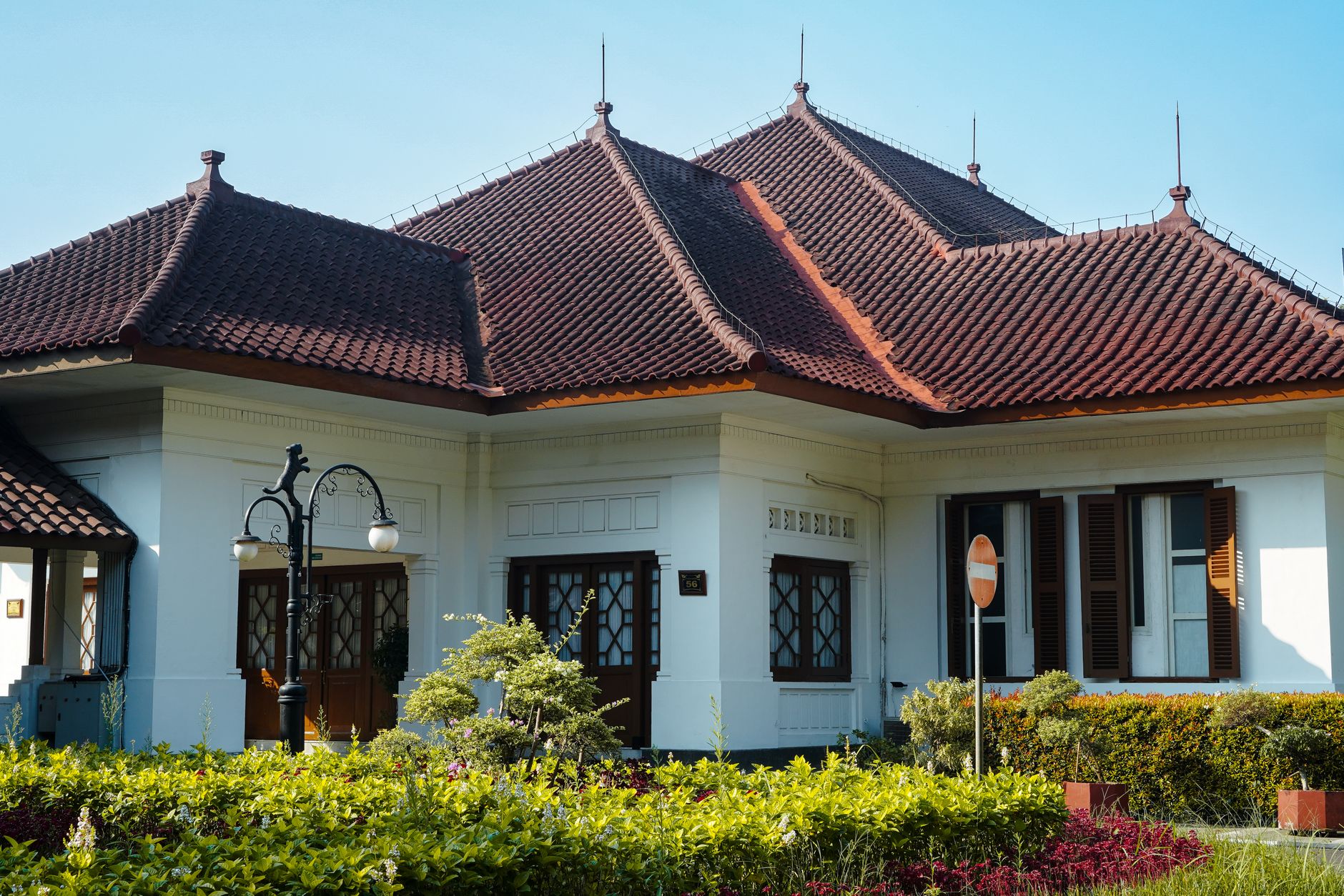 A white colonial villa with a red tiled roof and garden, the housing style at the heart of any Menteng Jakarta guide