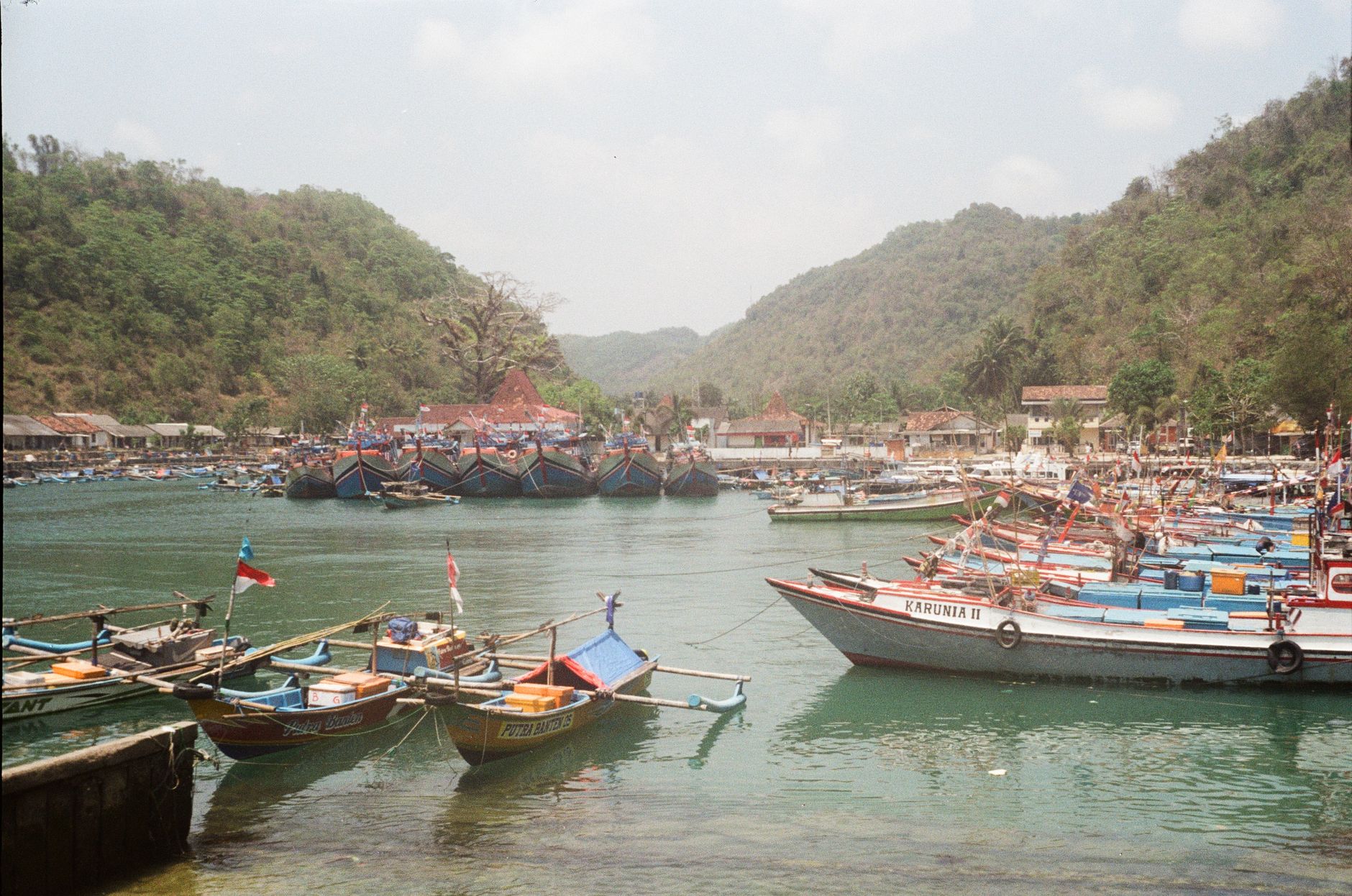 Brightly painted wooden fishing boats packed into a sheltered harbour on the south coast of Java