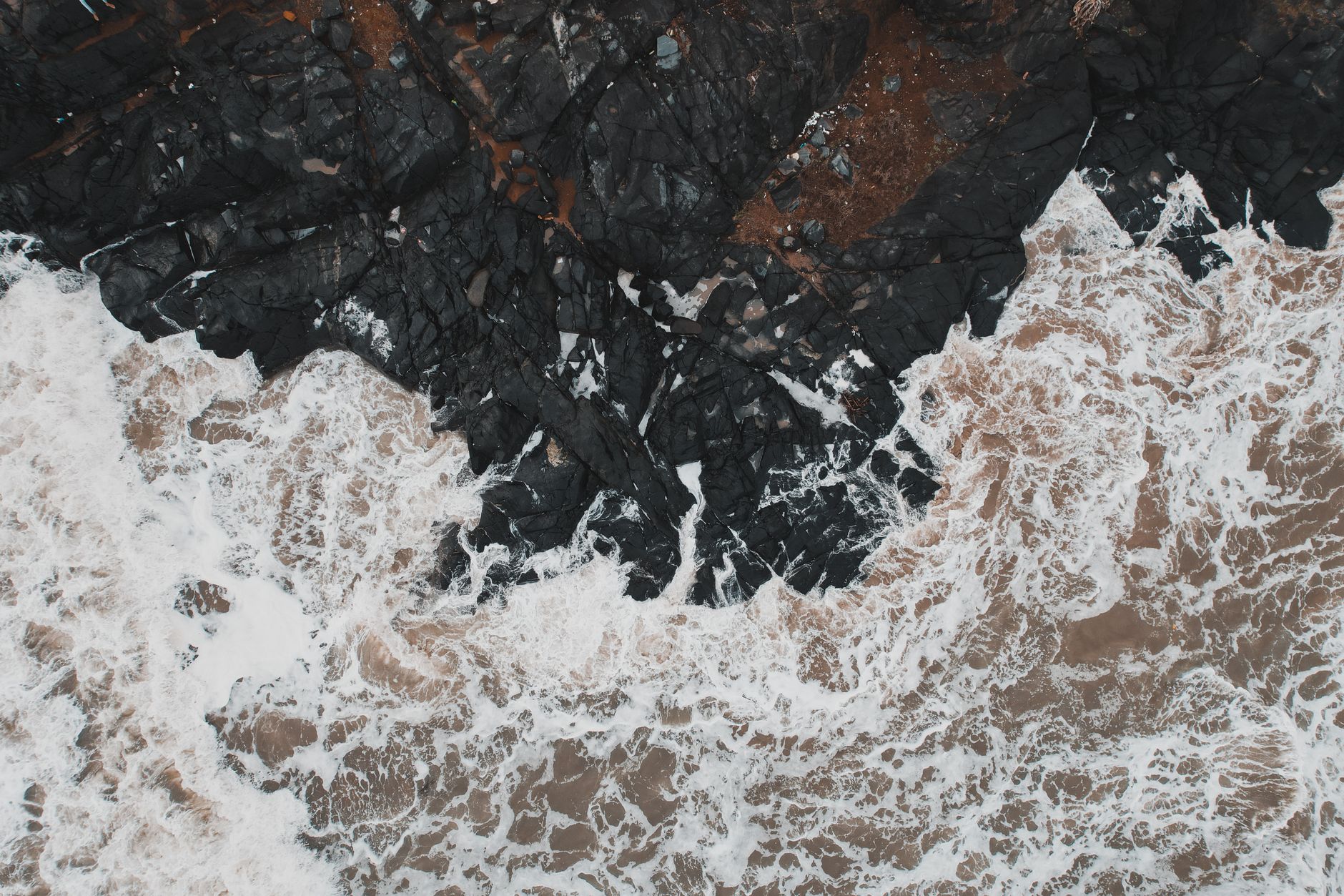 White water breaking over dark volcanic rock along an exposed coastline