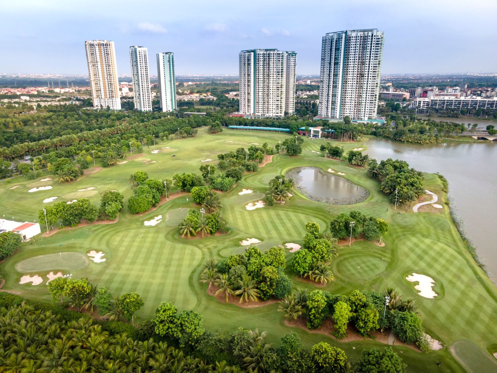 A landscaped golf course with water hazards and apartment towers behind, as at Pondok Indah Golf Course in Jakarta