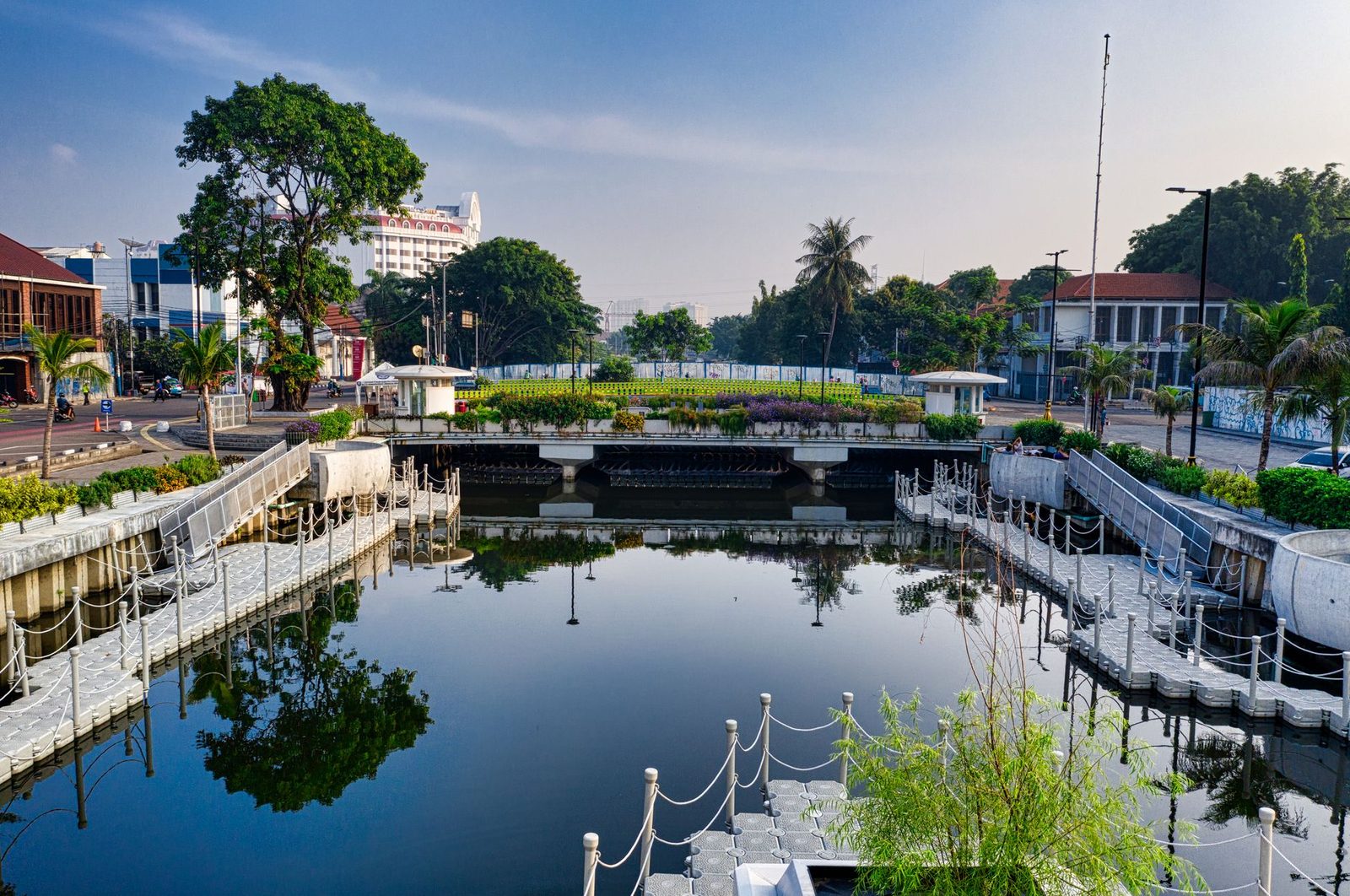 A landscaped canal crossed by a pedestrian bridge near the Dukuh Atas interchange in Jakarta
