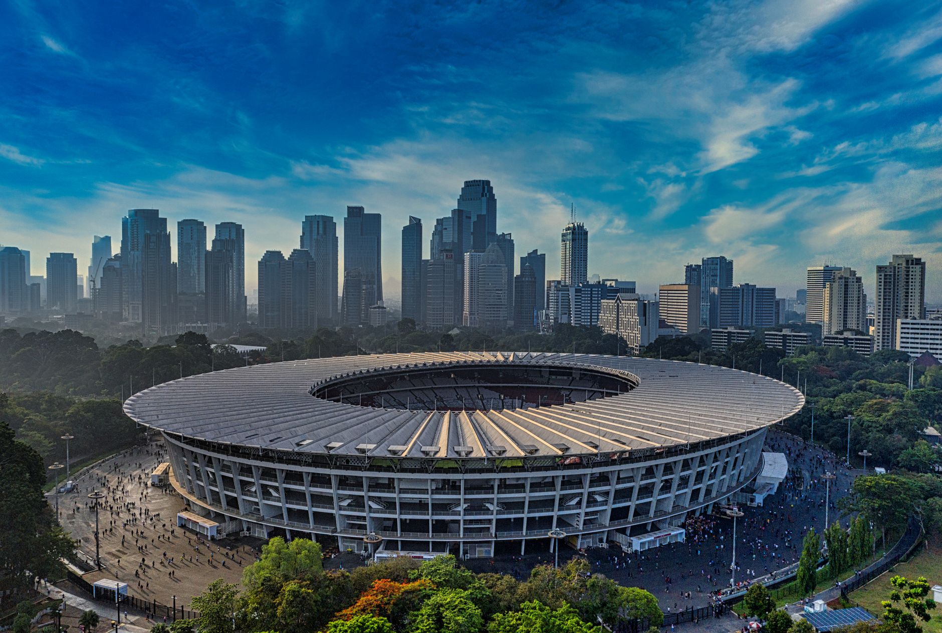 The Gelora Bung Karno main stadium with its cantilevered roof ring, seen against the Jakarta skyline in Senayan