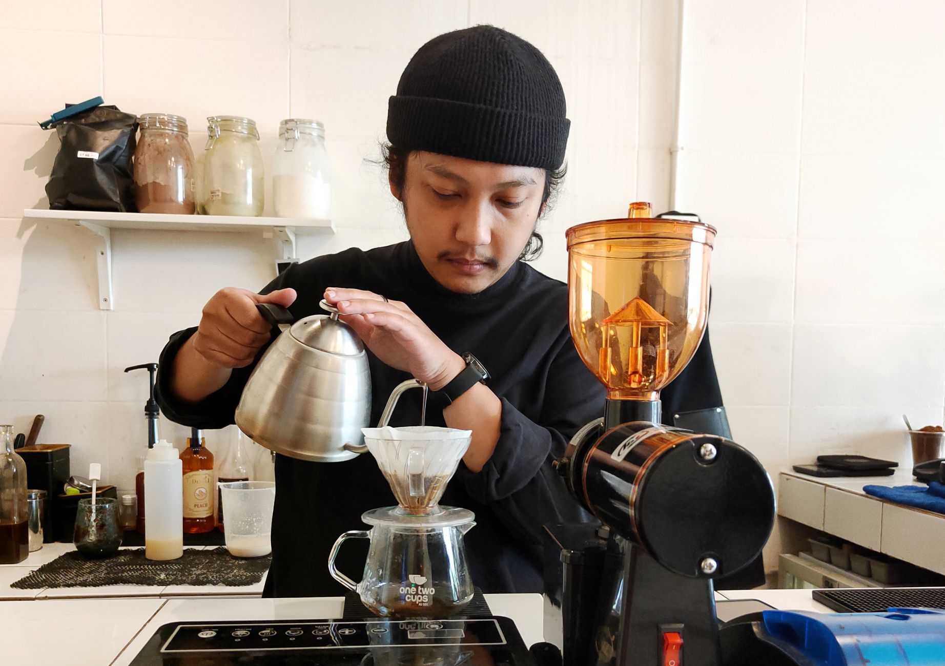 A barista pouring hot water over a filter coffee brewer in a South Jakarta specialty coffee shop