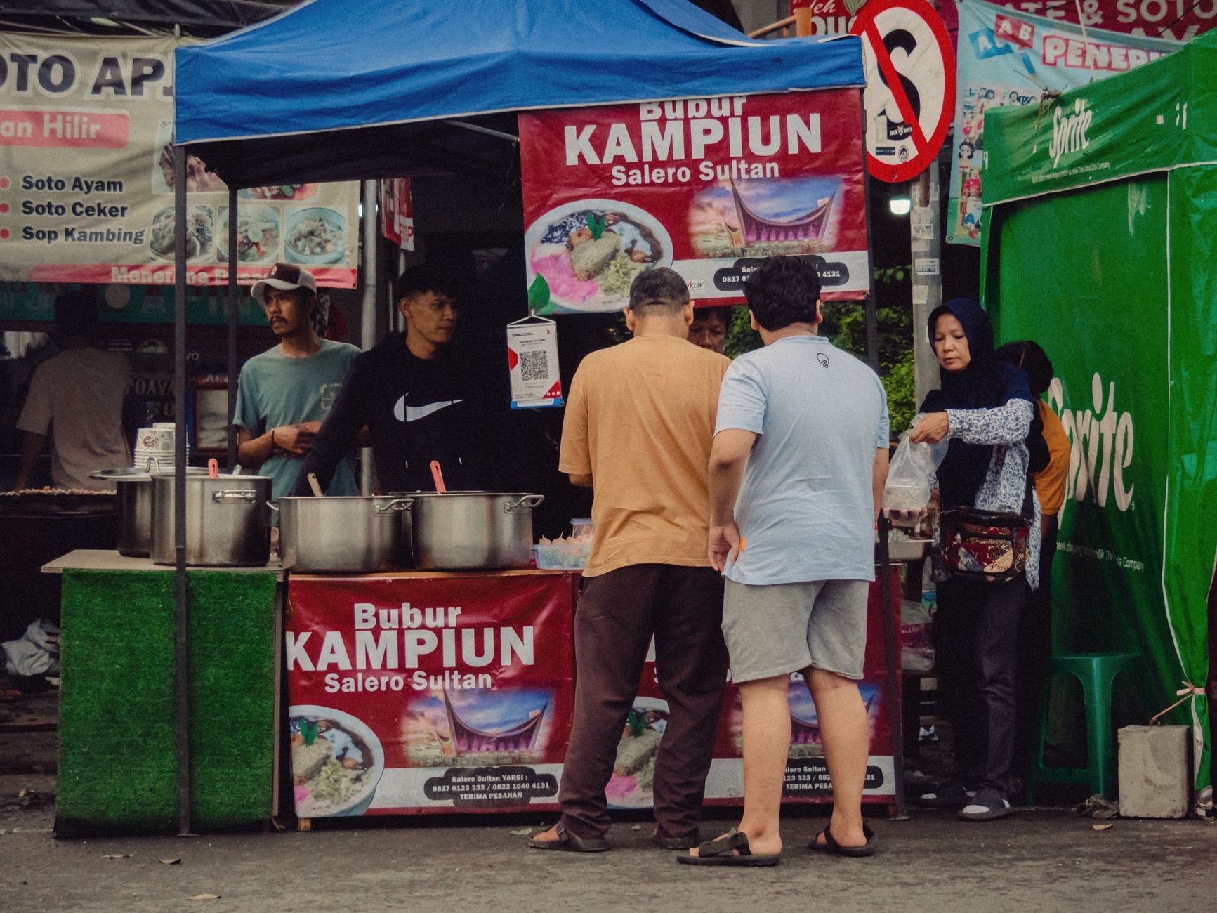 Customers queuing at a lit Indonesian street food stall in the evening in South Jakarta