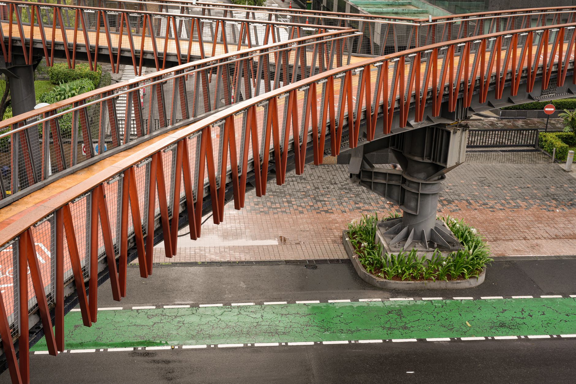 The curving orange Infinity Link Bridge crossing over a road at Tebet Eco Park in South Jakarta