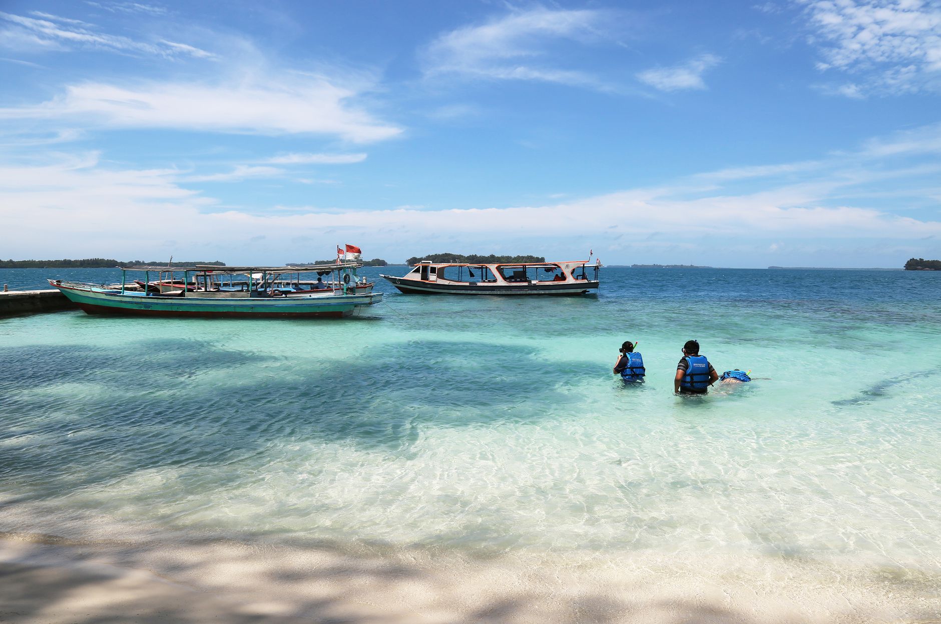 Wooden boats moored in shallow water off an island beach in Jakarta's Kepulauan Seribu regency