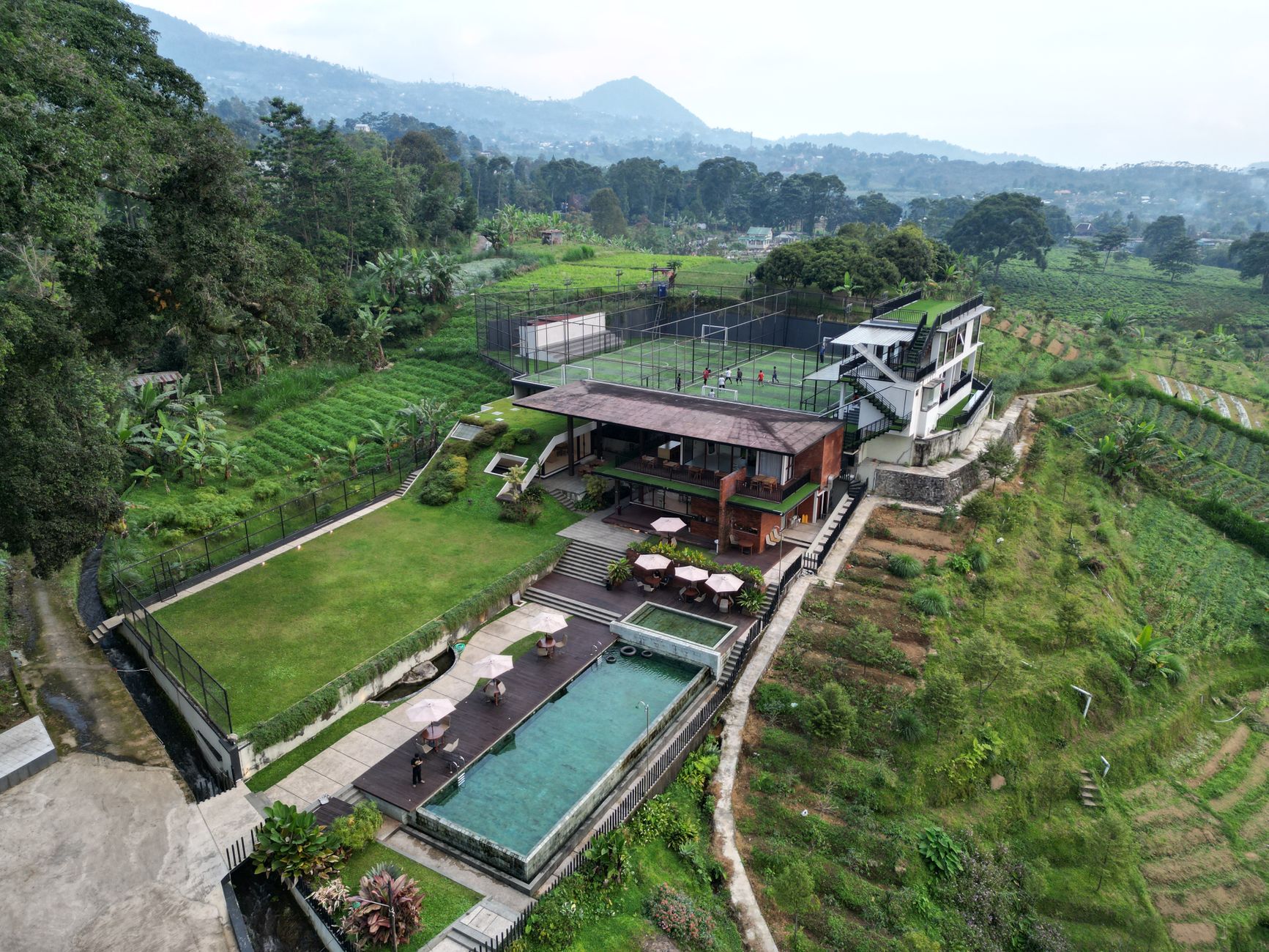 A villa with a swimming pool overlooking terraced farmland and mountains in the West Java highlands