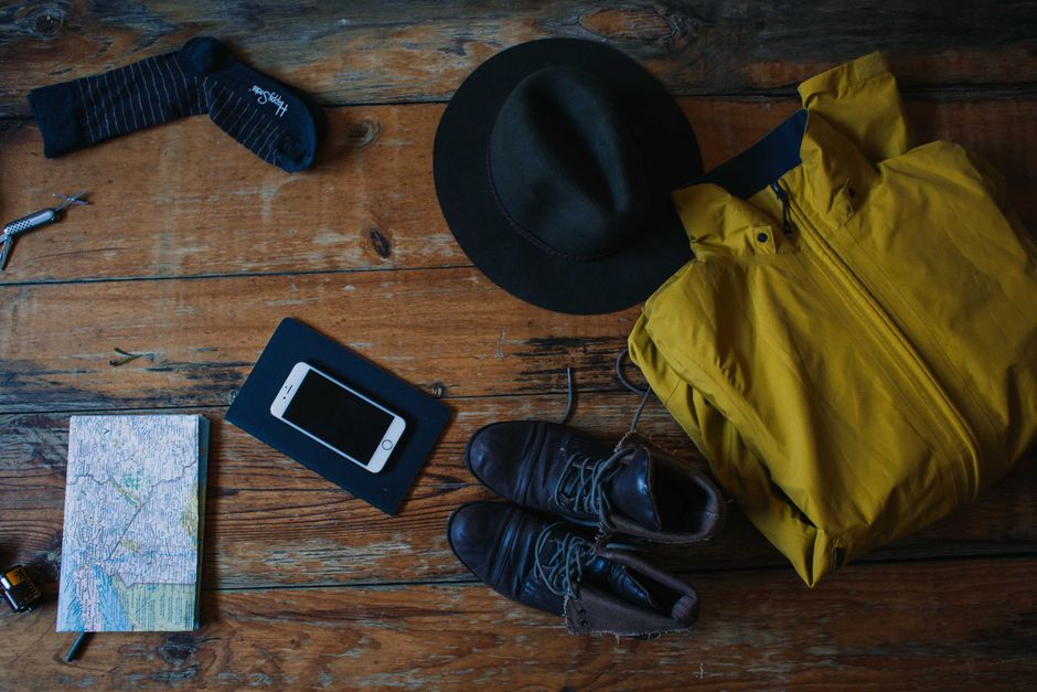 Flatlay of travel essentials including a map, phone, hat and jacket for a Jakarta trip