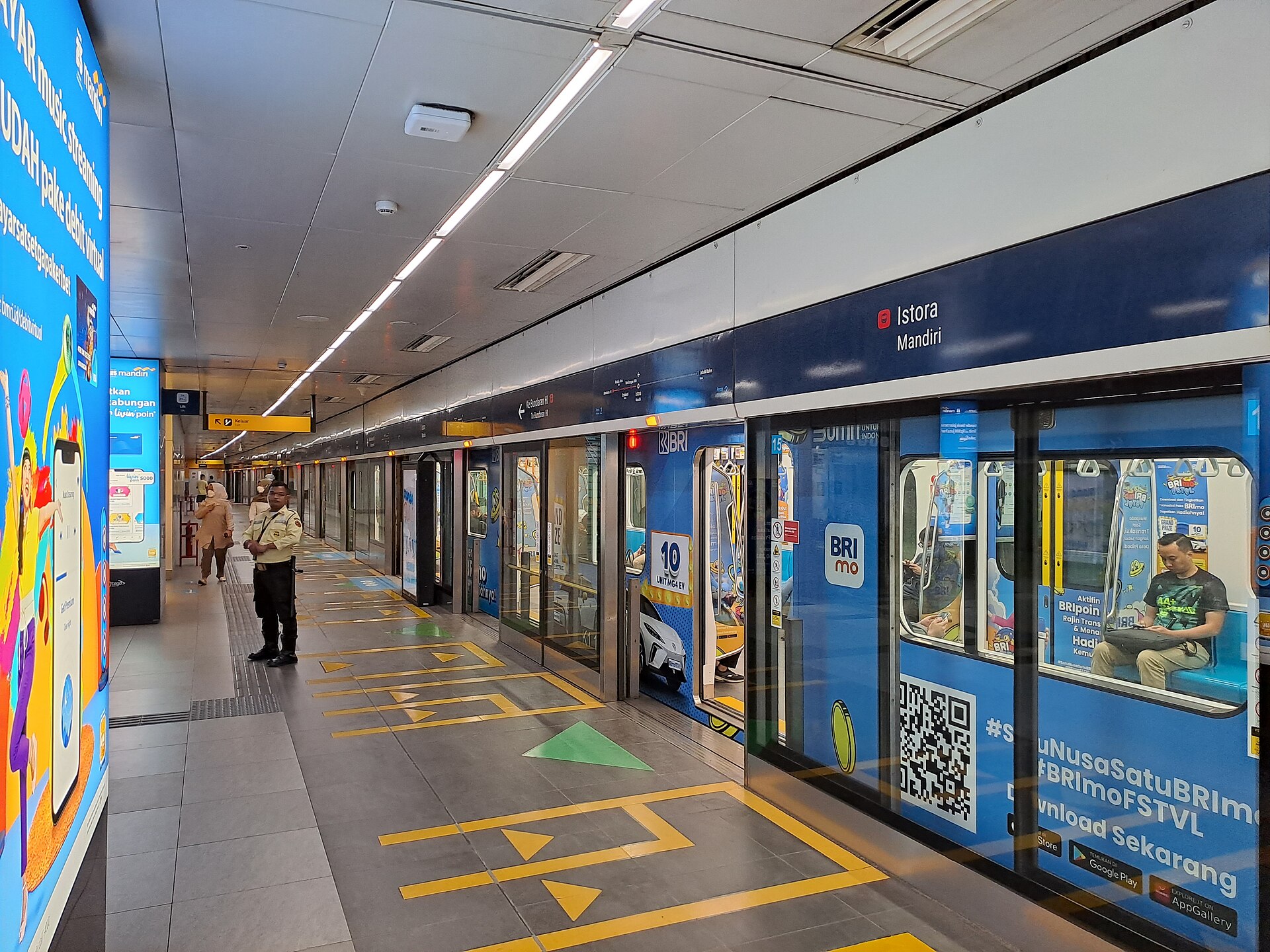 The platform at Istora Mandiri MRT station in Jakarta, with platform screen doors, station signage and a waiting passenger