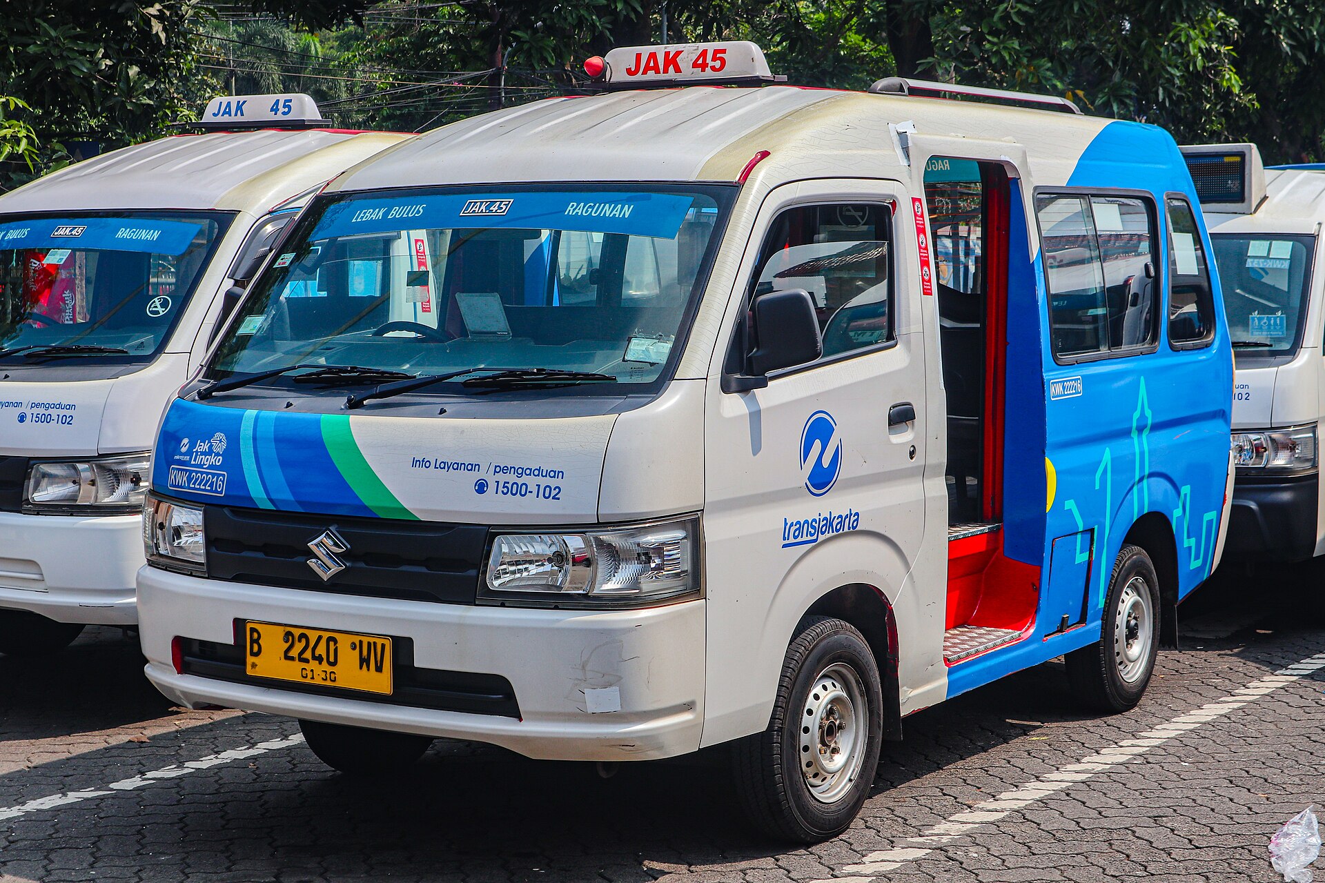 A white and blue Mikrotrans JakLingko minibus with route sign JAK 45, Lebak Bulus to Ragunan, parked with its sliding door open